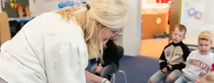 docent leest groep kinderen voor en loopt kring rond om het plaatje in het boek te laten zien