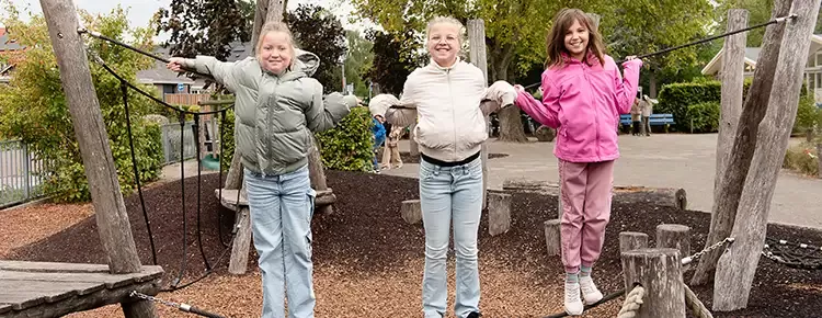3 meiden staan op een touwbrug en lachen